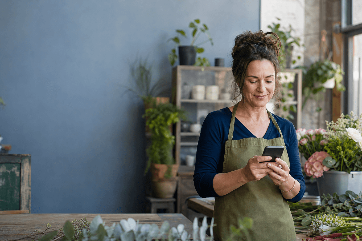 Local business owner checking her phone in her shop